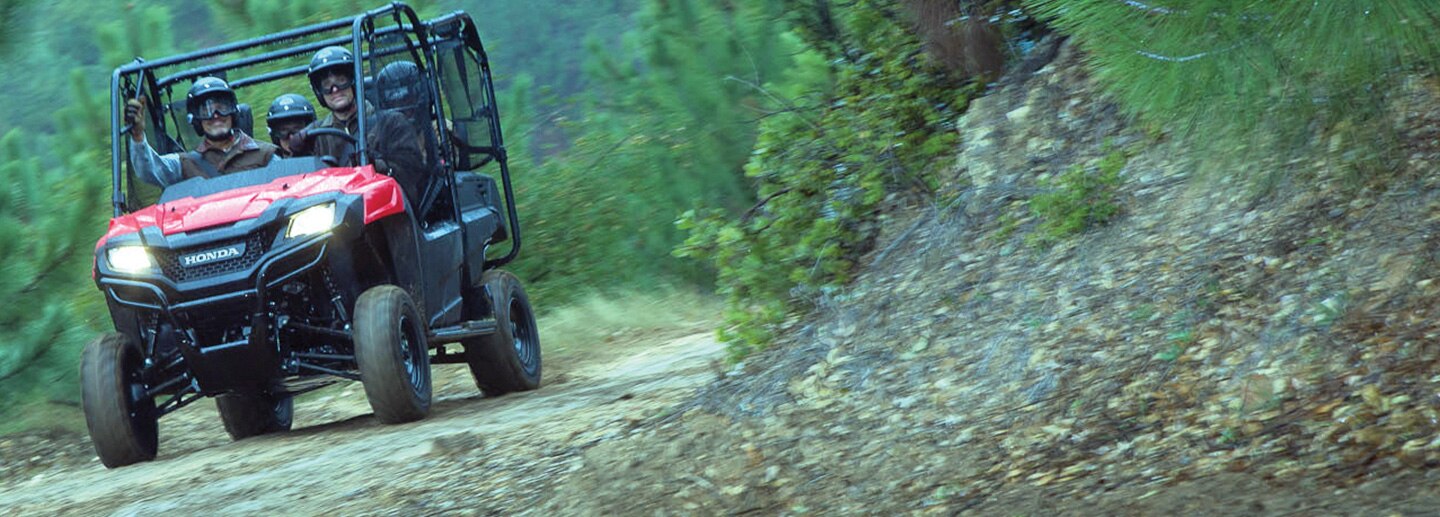 Image of four side-by-side riders driving happily along trail with lush green shrubbery