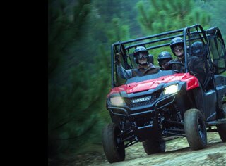 Image of four side-by-side riders driving happily along trail with lush green shrubbery