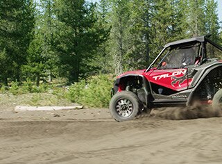 Four side-by-side riders driving happily along trail with lush green shrubbery
