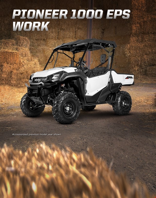 Pioneer 1000 EPS Work. Go beyond extraordinary. White side-by-side with hard roof and roll-up side nets parked in hay barn