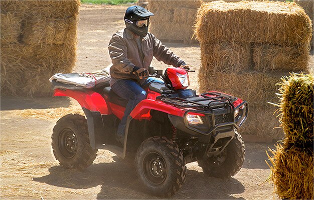 Image d'un homme pilotant un VTT TRX500 Rubicon IRS rouge sur un chemin de terre