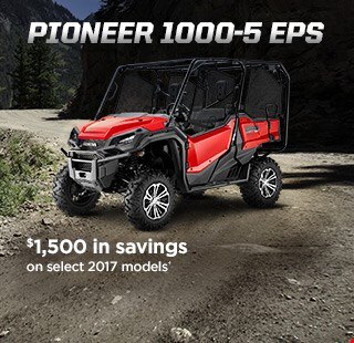 Pioneer 1000-5 EPS. Go beyond extraordinary. Image of a striking red side-by-side parked on wild off-road terrain among blue skies and snow capped mountain peaks