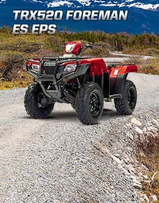 TRX500 Foreman ES EPS. The limitless legend. Image of orange ATV dramatically parked on gravel trail with majestic mountain peaks in background.